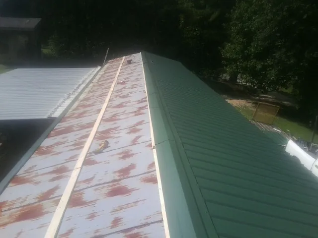 Old rusted panels beside newly installed green metal roofing — Wind Damage Roof Repair by Roofing Brothers in Indian Valley