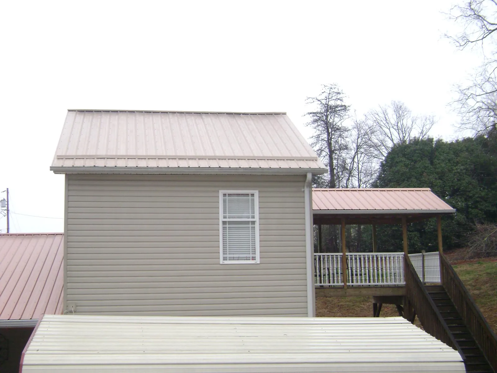 Tan metal roofs on a two story addition and attached porch, from a Roof Replacement job in Indian Valley
